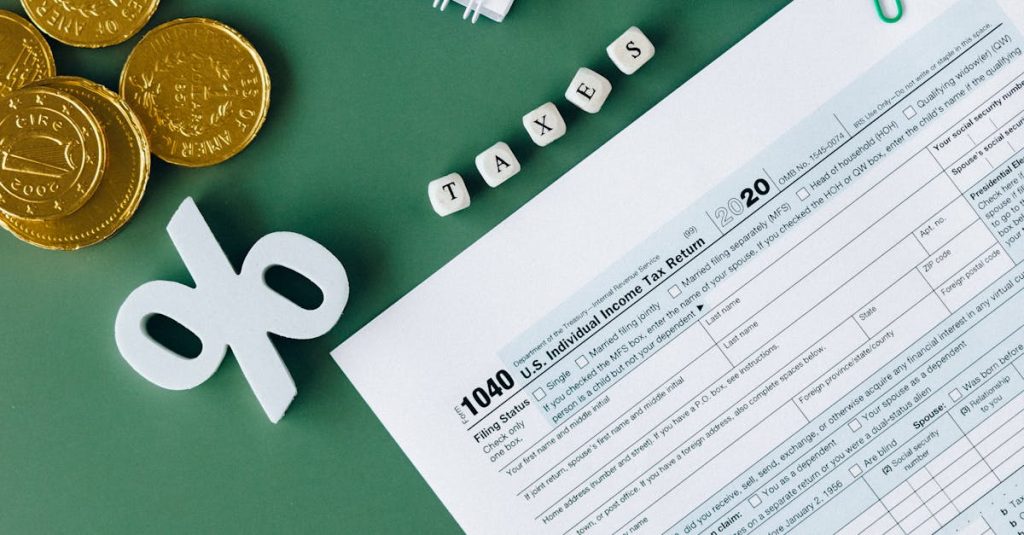 Tax documents and office supplies on green surface, indicating tax season planning and finance concepts.