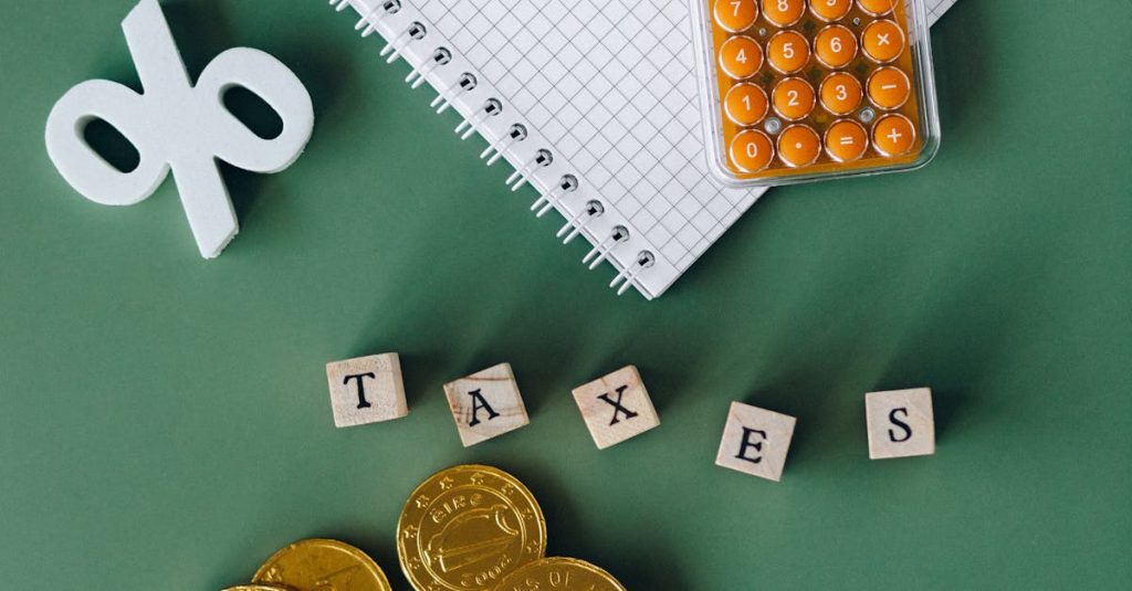 Flat lay of calculator, gold coins, notebook, and tax symbols on a green background.